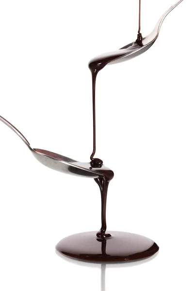 巧克力浇入一把勺子和从它到另一个勺子隔离对惠特 — 图库照片