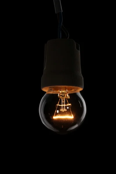 Uma lâmpada acesa no fundo preto — Fotografia de Stock