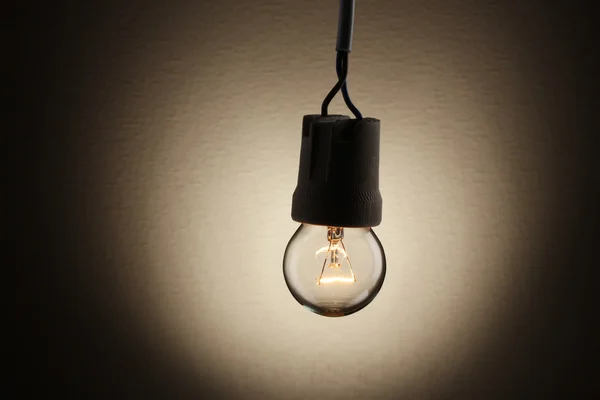 A lit light bulb on brown background — Stock Photo, Image