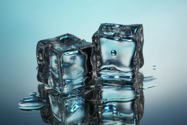 Derretendo cubos de gelo no fundo azul — Fotografia de Stock