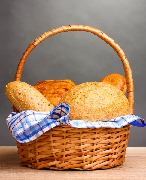 Pâine delicioasă în coș pe masă de lemn pe fundal gri — Fotografie, imagine de stoc