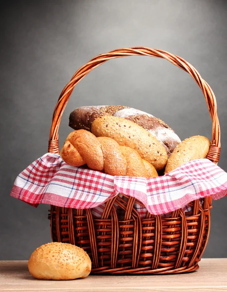 회색 배경에 나무 테이블에 바구니에 맛 있는 빵 — 스톡 사진