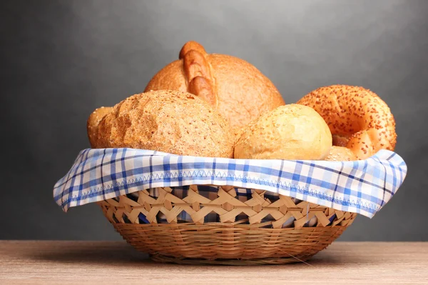 Leckeres Brot im Korb auf Holztisch auf grauem Hintergrund — Stockfoto