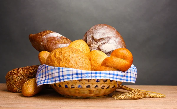 Delicioso pan en cesta y orejas sobre mesa de madera sobre fondo gris —  Fotos de Stock