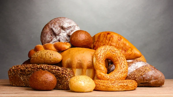 灰色の背景に木製のテーブル上に美味しいパン — ストック写真