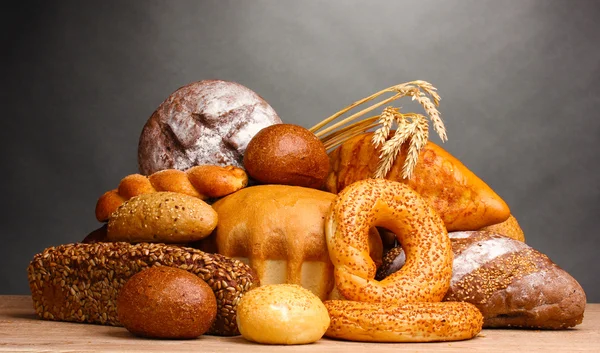 Gri zemin üzerine ahşap masa üstünde lezzetli ekmek — Stok fotoğraf