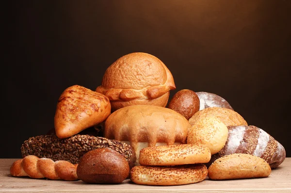 Leckeres Brot auf Holztisch auf braunem Hintergrund — Stockfoto