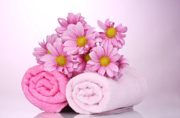 Havlu ve pembe bir arka plan üzerine güzel çiçekler — Stok fotoğraf