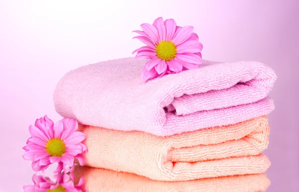 Полотенца и красивые цветы на розовом фоне — стоковое фото