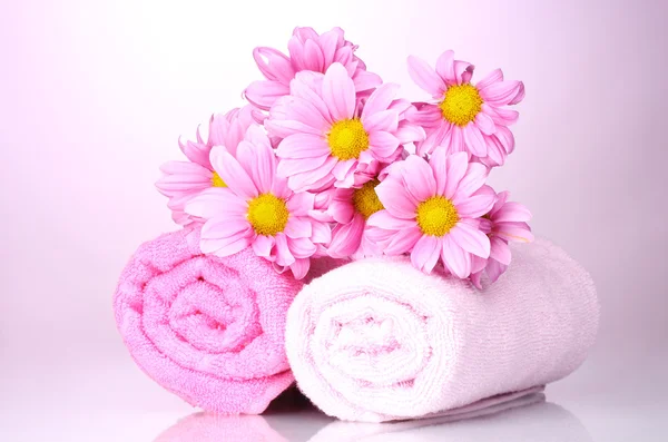 Asciugamani e bellissimi fiori su sfondo rosa — Foto Stock