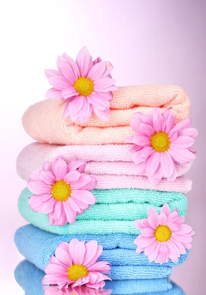 Handtücher und schöne Blumen auf rosa Hintergrund — Stockfoto