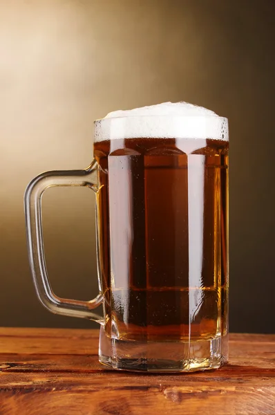 Bierkrug auf Holztisch auf braunem Hintergrund — Stockfoto
