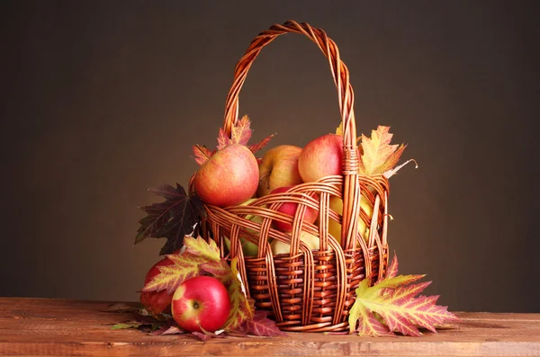 Mooie herfst oogst in mand en bladeren op bruine achtergrond — Stockfoto