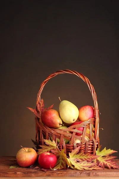 Прекрасний осінній урожай в кошику і листя на коричневому фоні — стокове фото