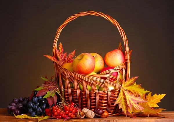 Schöne Herbsternte in Korb und Blättern auf braunem Hintergrund — Stockfoto