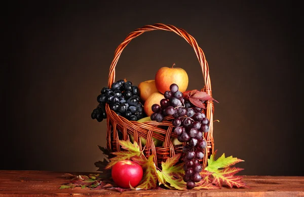 Krásné podzimní sklizeň v koši a listy na hnědé pozadí — Stock fotografie
