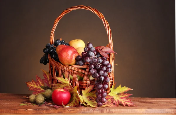 Mooie herfst oogst in mand en bladeren op bruine achtergrond — Stockfoto