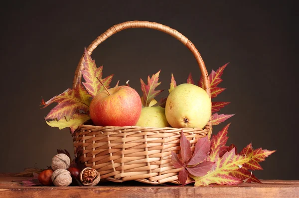 Schöne Herbsternte in Korb und Blättern auf braunem Hintergrund — Stockfoto