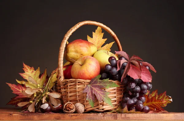 Hermosa cosecha de otoño en cesta y hojas sobre fondo marrón — Foto de Stock