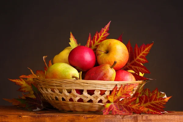 Beautiful autumn harvest in basket and leaves on brown background — Stock Photo, Image