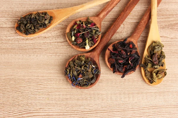 Διαφορετικά είδη πράσινο και μαύρο στεγνώσει τσάι σε κουτάλια στο ξύλινο τραπέζι — Φωτογραφία Αρχείου