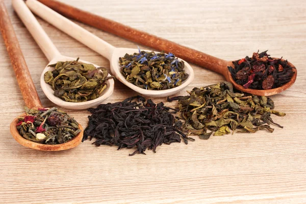 Különböző típusú száraz zöld és fekete teát, a kanál a fából készült háttér — Stock Fotó