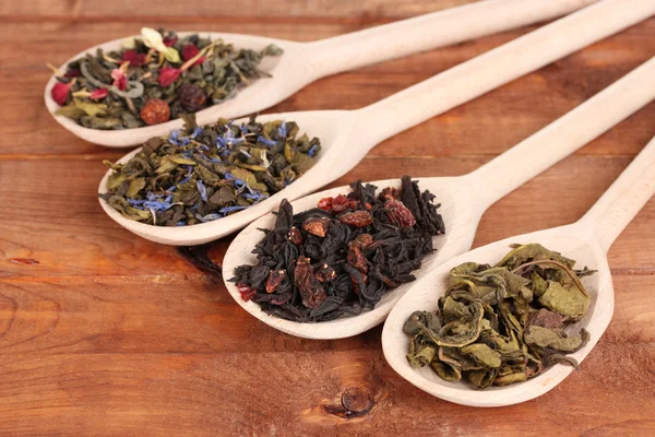 Різні види сухого зеленого і чорного чаю в ложках на дерев'яному фоні — стокове фото