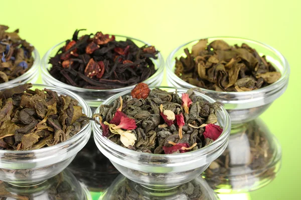 Diferentes tipos de té seco verde y negro sobre fondo verde — Foto de Stock