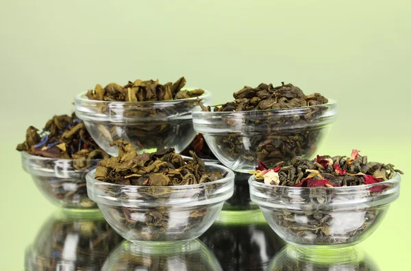 Различные виды зеленого и черного сухого чая на зеленом фоне — стоковое фото