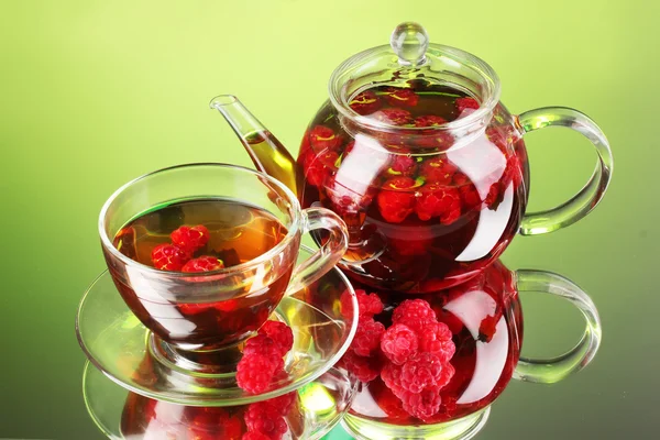 Svart frukt hallon te i glas tekanna och kopp på grön bakgrund — Stockfoto