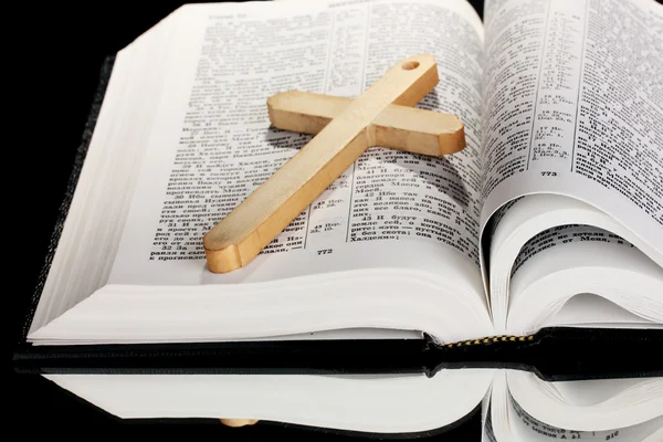 Biblia russa e cruz de madeira sobre fundo preto — Fotografia de Stock