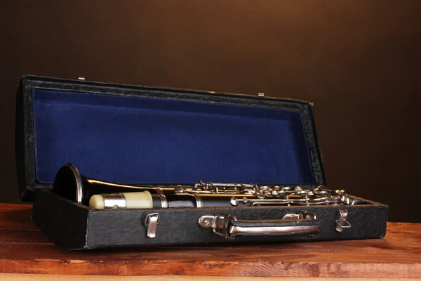 Old clarinet in case on wooden table on brown background — Stock Photo, Image