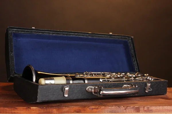 Stary klarnet w przypadku na drewnianym stole na brązowym tle — Zdjęcie stockowe