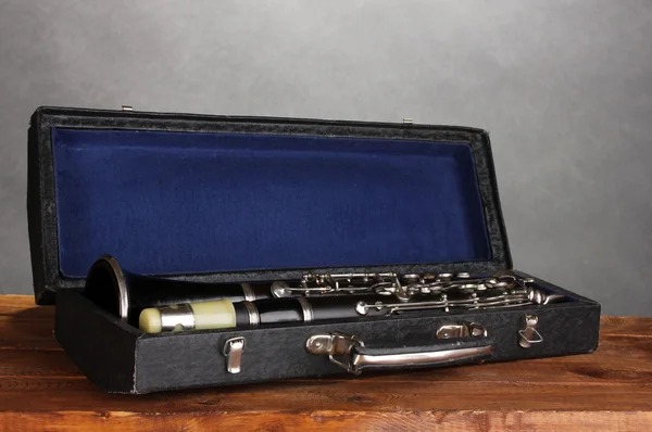 Stary klarnet w przypadku na drewnianym stole na szarym tle — Zdjęcie stockowe