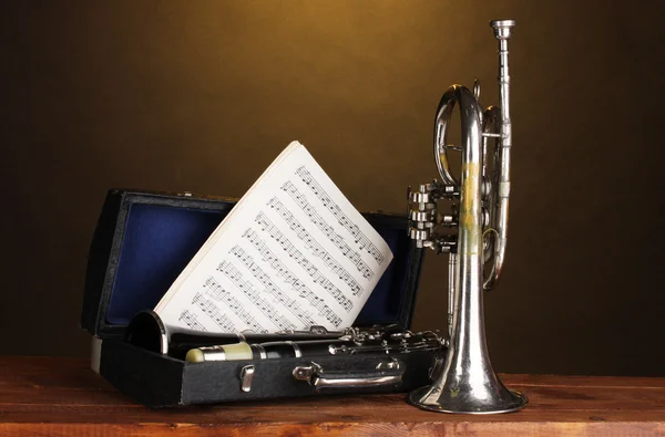 Trompetă antică și clarinet în cazul în care pe masa de lemn pe fundal maro — Fotografie, imagine de stoc