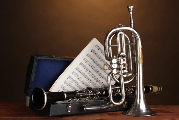 Antik trombita és a klarinét, abban az esetben, a fából készült asztal barna háttér — Stock Fotó
