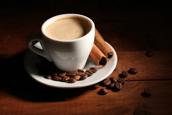 Tasse mit Kaffee, Zimt und Kaffeebohnen auf Holztisch — Stockfoto