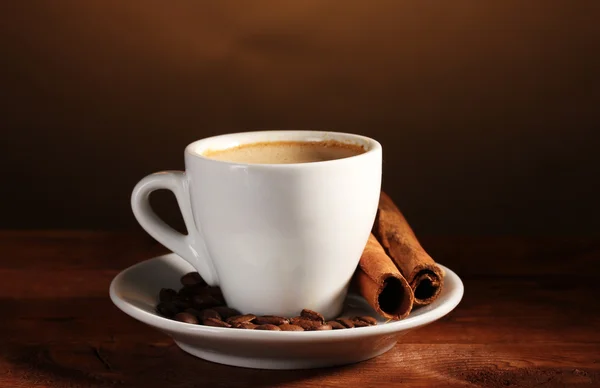 Tasse mit Kaffee, Zimt und Kaffeebohnen auf Holztisch auf braunem Backblech — Stockfoto