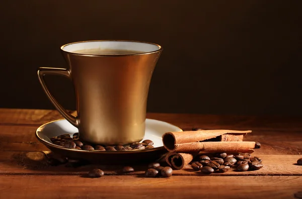 金杯在棕色的木桌上的咖啡、 肉桂和咖啡豆 — 图库照片