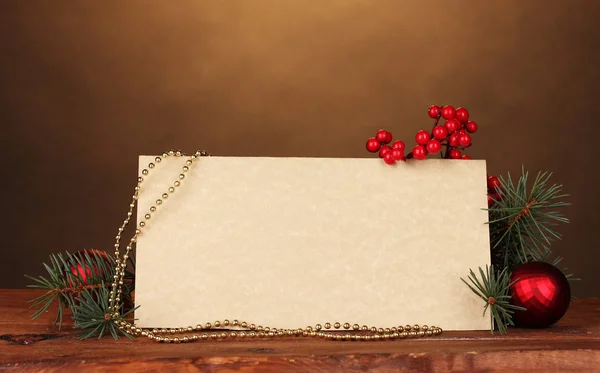Cartolina bianca, palline di Natale e abete su tavolo di legno su dorso marrone Foto Stock Royalty Free