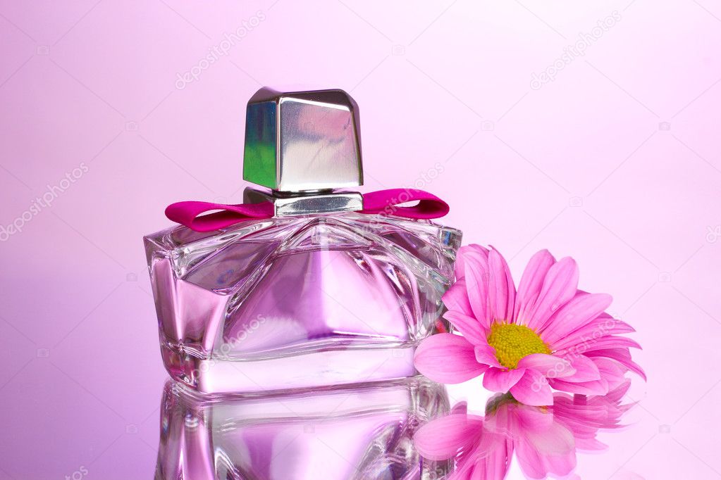 Women's perfume in beautiful bottle and flower on pink background