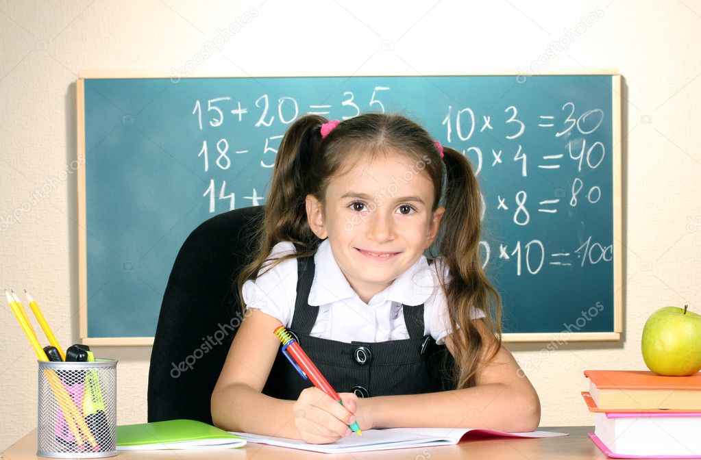 Little schoolchild in classroom near blackboard