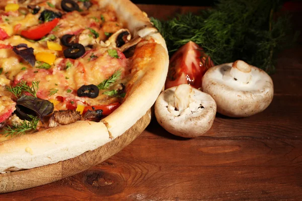 stock image Delicious pizza and vegetables on wooden table