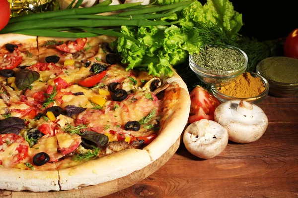 Delicious pizza, vegetables and spices on wooden table — Stock Photo, Image