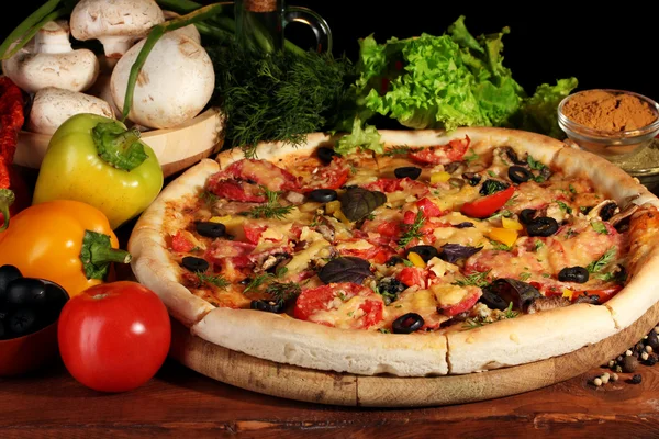 Heerlijke pizza, groenten en kruiden op houten tafel op bruine achtergrond — Stockfoto