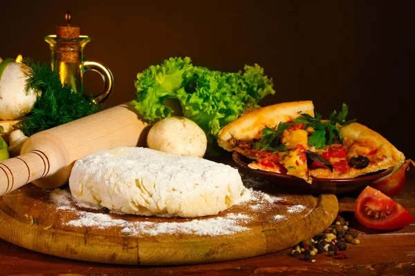 Deliciosa masa de pizza, especias y verduras en la mesa de madera en respaldo marrón — Foto de Stock