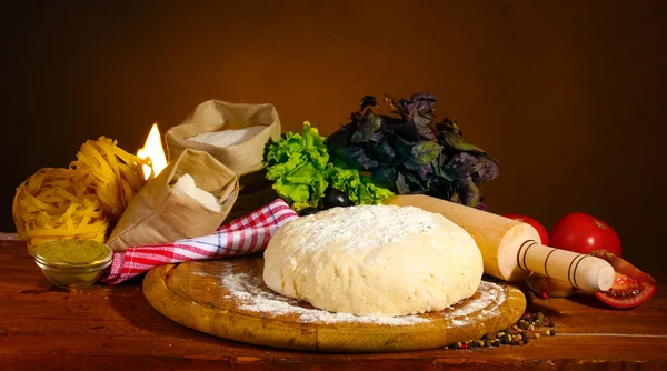 Ingrediënten voor zelfgemaakte pizza op houten tafel op bruine achtergrond — Stockfoto