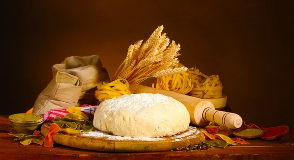 Ingrediënten voor zelfgemaakte pasta op houten tafel op bruine achtergrond — Stockfoto