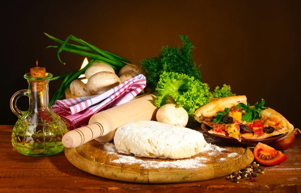 Delicious pizza dough, spices and vegetables on wooden table on brown backg — Stock Photo, Image