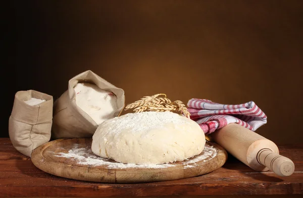 Dough și pungi cu făină pe masă de lemn pe fundal maro — Fotografie, imagine de stoc